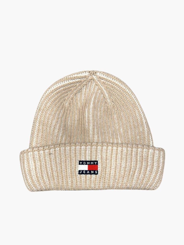 כובע גרב (Beanie) סרוג של מותג טומי ג'ינס בגווני בז' ולבן עם לוגו הרקמה האייקוני בחזית, מעניק מראה חורפי אופנתי ומחמם.