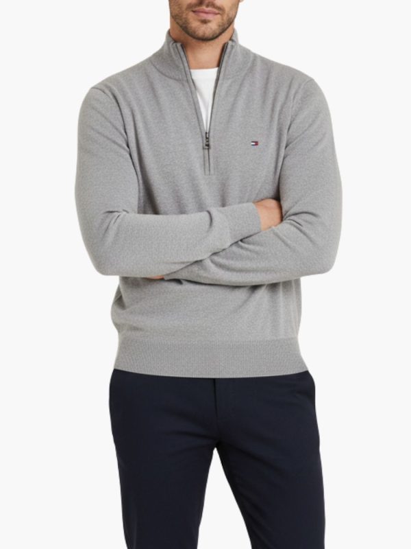 סריג אפור של טומי הילפיגר עם צווארון גבוה ורוכסן קצר בחזית ולוגו קטן רקום בצד שמאל של החזה