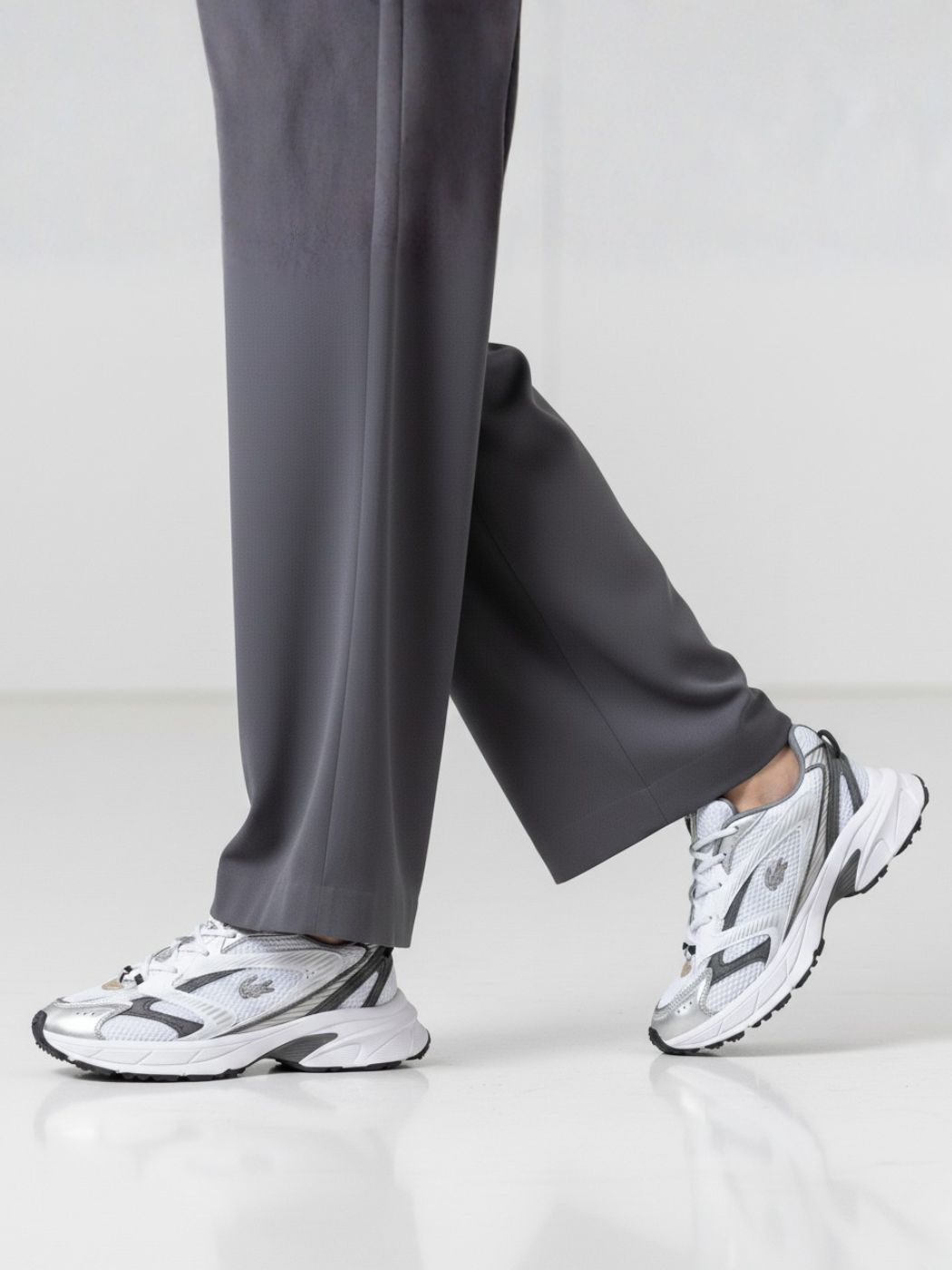 נעלי ספורט לבנות של לקוסט עם שילובי כסף ושחור, רשת נושמת ולוגו התנין בצד