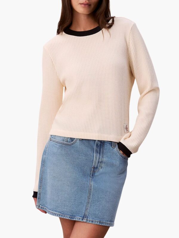 סריג בז' של קלווין קליין עם מרקם ריב, צווארון וסיומת שחורים ותג לוגו CK בתחתית הצדית