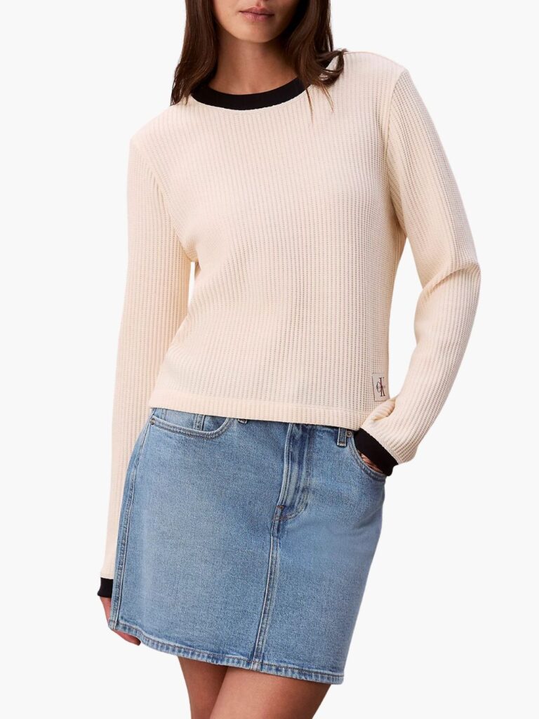 סריג בז' של קלווין קליין עם מרקם ריב, צווארון וסיומת שחורים ותג לוגו CK בתחתית הצדית