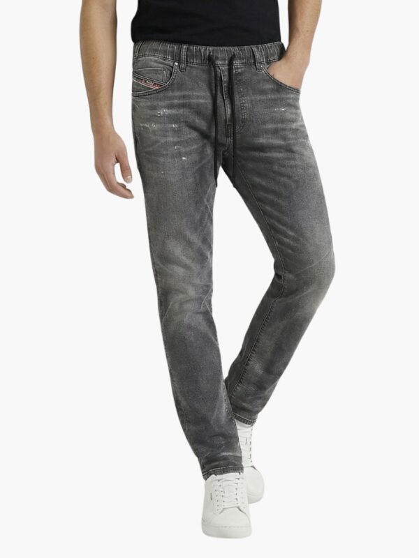 ג’ינס אפור של דיזל בגזרה משוחררת עם שרוך מותן, דיטיילים משופשפים וכיס קדמי עם תג אדום.