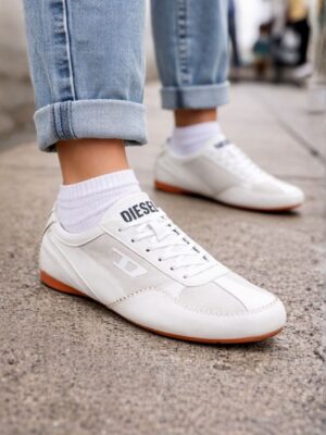 נעלי סניקרס לבנות של דיזל עם שילוב עור וזמש בהיר, שרוכים לבנים, לוגו דיזל בצד וסוליה חומה שטוחה.