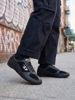 נעלי סניקרס שחורות של דיזל עם שילוב עור וזמש, שרוכים שחורים, לוגו דיזל לבן בצד וסוליה שטוחה.