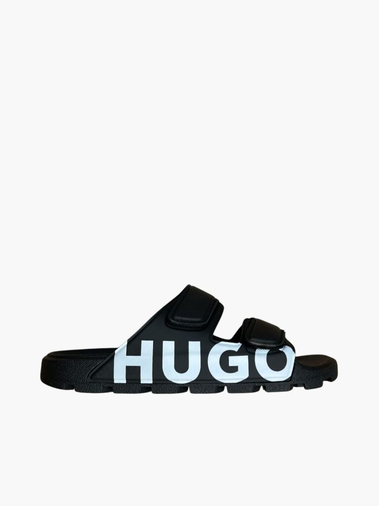 כפכפי סליידס מעוצבים לגבר מבית HUGO בצבע שחור עם שתי רצועות סקוץ' ולוגו ענק לבן בצד – סטייל אורבני ונוחות מקסימלית.