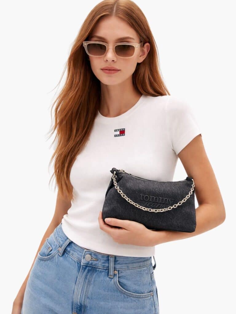 תיק כתף קטן ומעוצב מבית טומי ג'ינס (Tommy Jeans) מבד דנים שחור שטוף, עם לוגו רקום ושרשרת כסופה דקורטיבית למראה אורבני ועדכני.