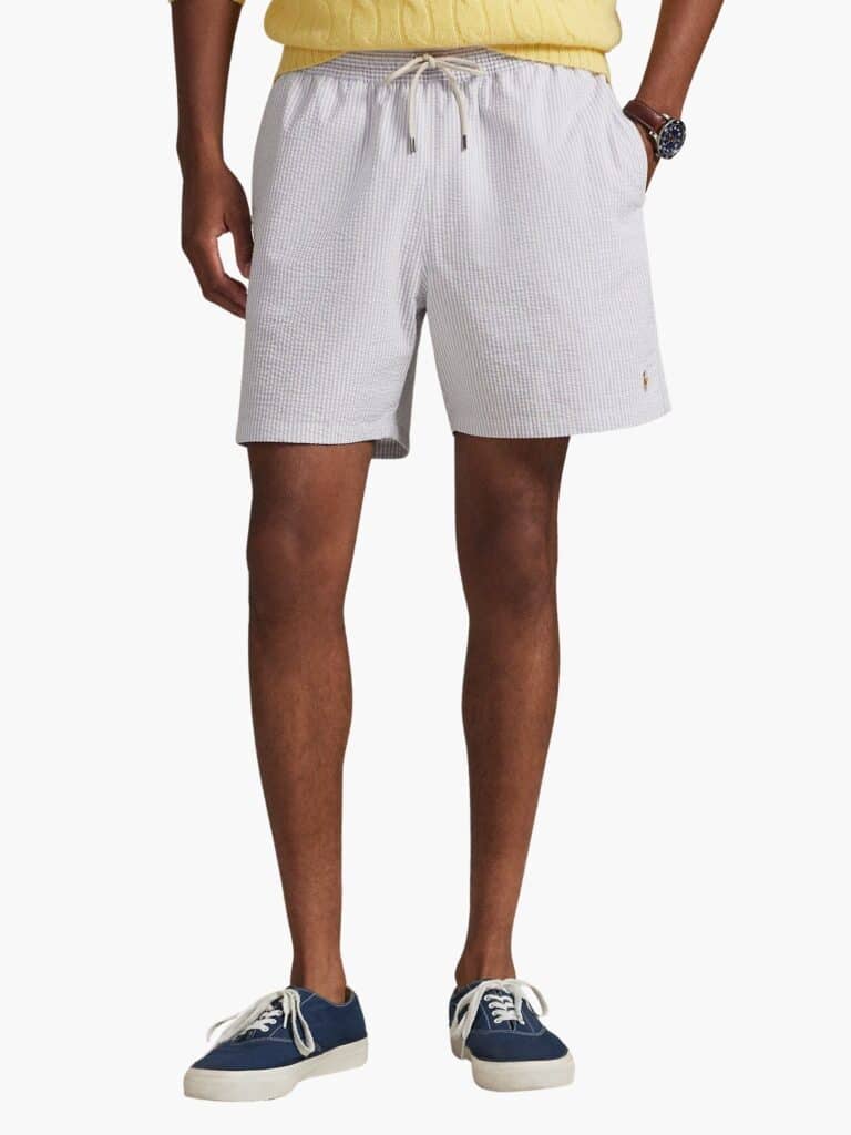 מכנס בגד ים יוקרתי לגבר מבית Polo Ralph Lauren בעיצוב פסים בצבעי סגול עדין ולבן, עשוי בד סירסאקר (מכווץ) עם לוגו הפרש הצבעוני.