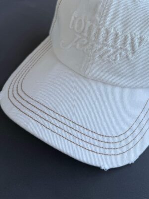 תקריב על המצחייה של כובע Tommy Jeans המציג את גימור הקרעים האופנתי.