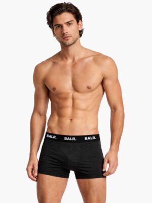 דוגמן לובש תחתון BALR שחור קצר מכותנה נמתחת עם לוגו בולט.