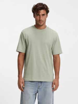 גבר לובש חולצת טי הוגו בצבע ירוק בהיר.